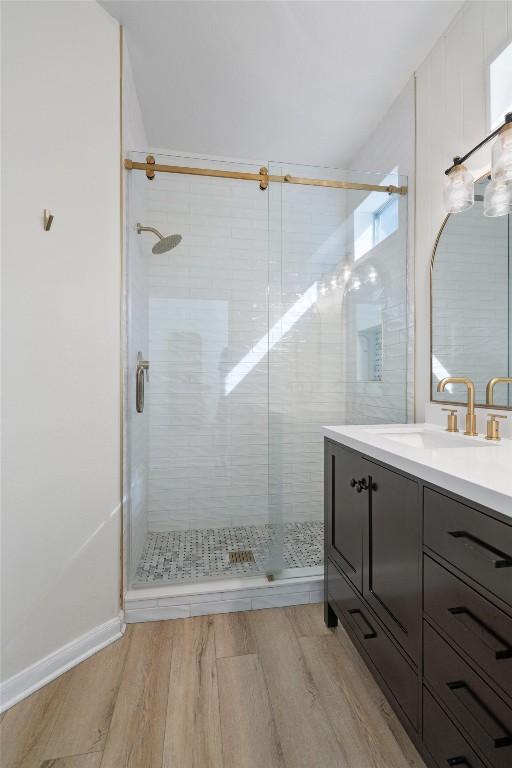 full bath with vanity, wood finished floors, and a stall shower