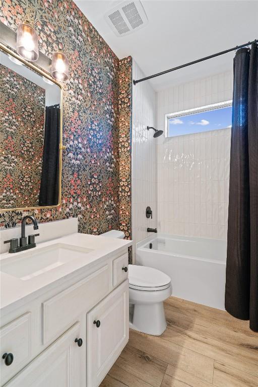 bathroom with visible vents, wallpapered walls, toilet, shower / tub combo, and vanity