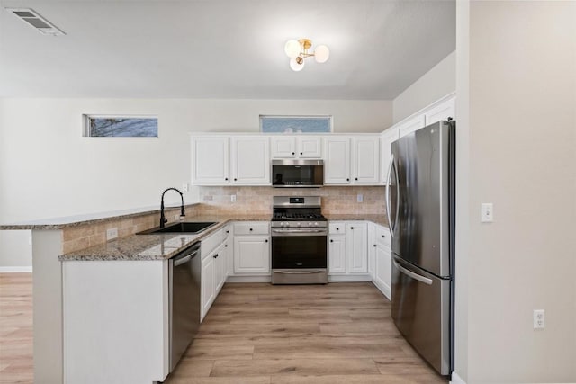 kitchen with visible vents, light wood-style flooring, a sink, stainless steel appliances, and white cabinetry