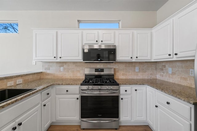 kitchen featuring decorative backsplash, white cabinets, appliances with stainless steel finishes, and a healthy amount of sunlight