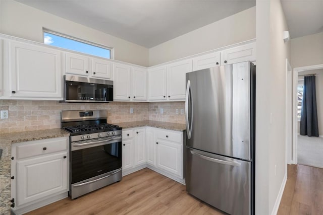 kitchen featuring decorative backsplash, white cabinets, and appliances with stainless steel finishes