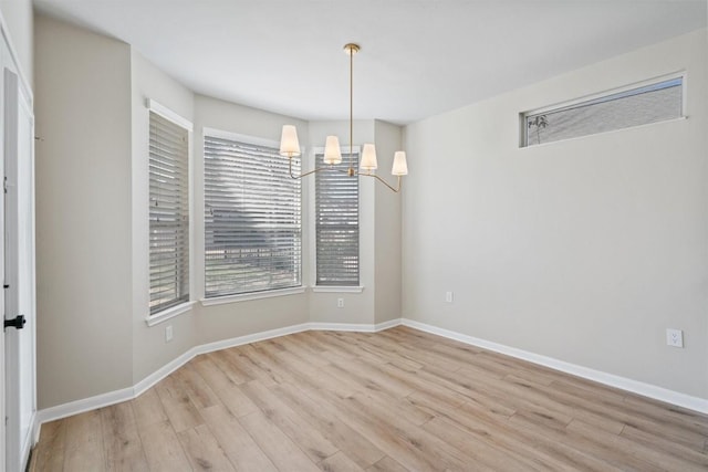 unfurnished dining area featuring a chandelier, baseboards, and wood finished floors