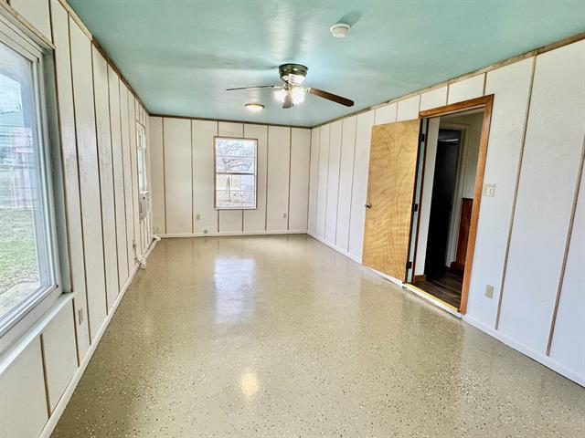 empty room with a decorative wall, a ceiling fan, and speckled floor