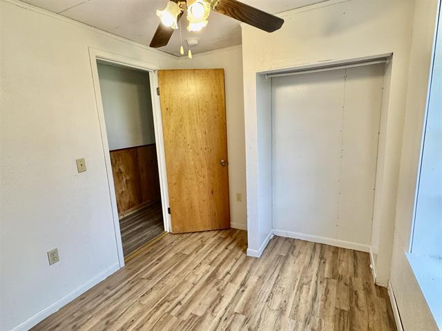 unfurnished bedroom featuring a ceiling fan, wood finished floors, a closet, and baseboards