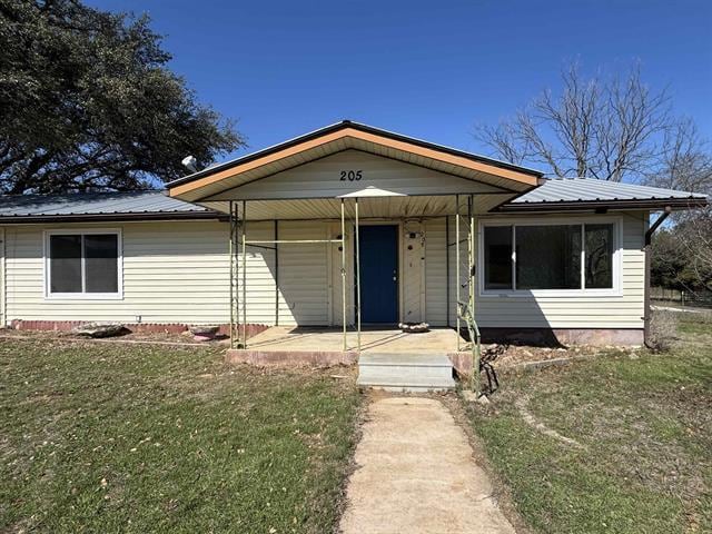 view of front of property featuring a front yard, covered porch, and metal roof