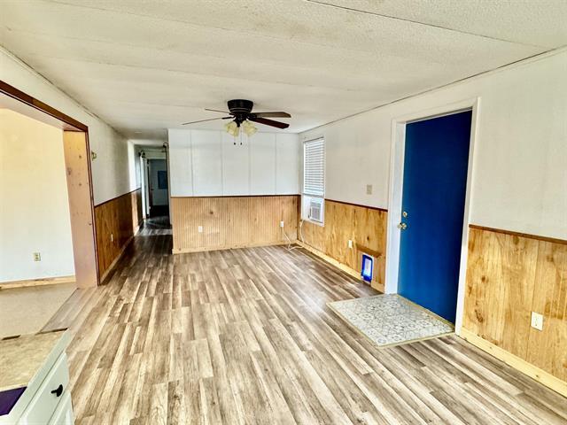 unfurnished room with a wainscoted wall, light wood-style floors, and wooden walls