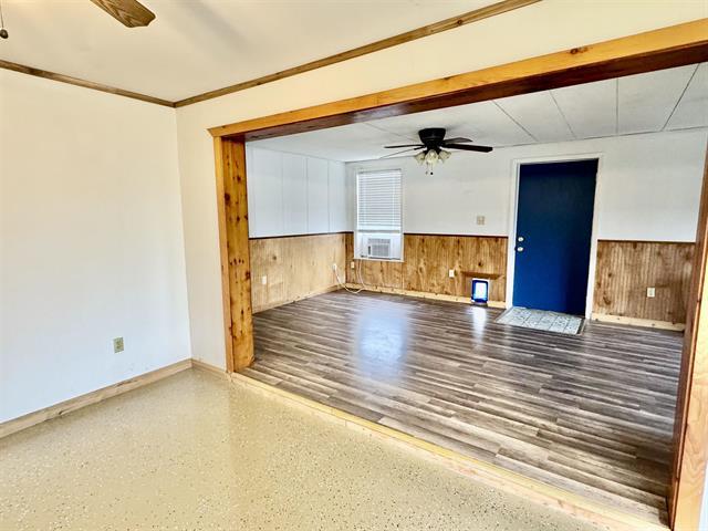 spare room featuring a wainscoted wall, wood walls, cooling unit, and ceiling fan