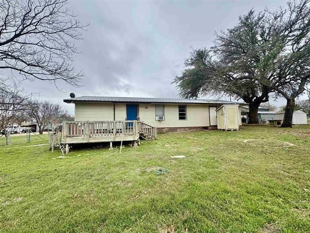 back of house featuring a yard, an outdoor structure, a deck, and a shed