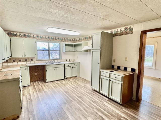 kitchen featuring light wood finished floors, a textured ceiling, light countertops, and a sink