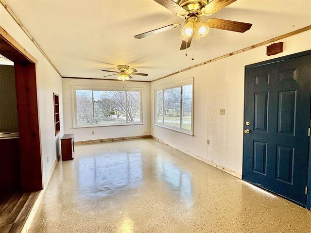 interior space featuring speckled floor, baseboards, a ceiling fan, and crown molding