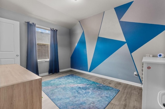 interior space with vaulted ceiling, wood finished floors, and baseboards