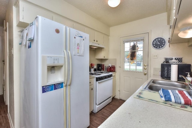 kitchen with white appliances, dark wood finished floors, light countertops, under cabinet range hood, and a textured ceiling