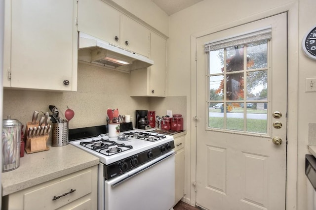 kitchen featuring under cabinet range hood, light countertops, a wealth of natural light, and white gas range oven