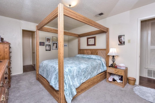 bedroom featuring visible vents, carpet floors, and a textured ceiling