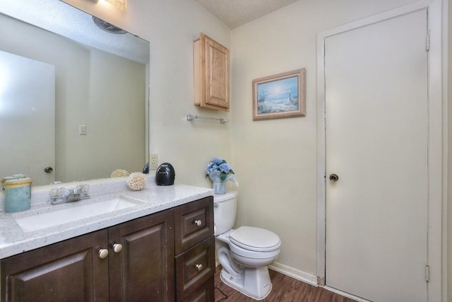 half bath with vanity, toilet, and wood finished floors