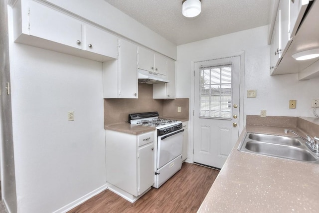 kitchen featuring gas range gas stove, under cabinet range hood, wood finished floors, a textured ceiling, and a sink