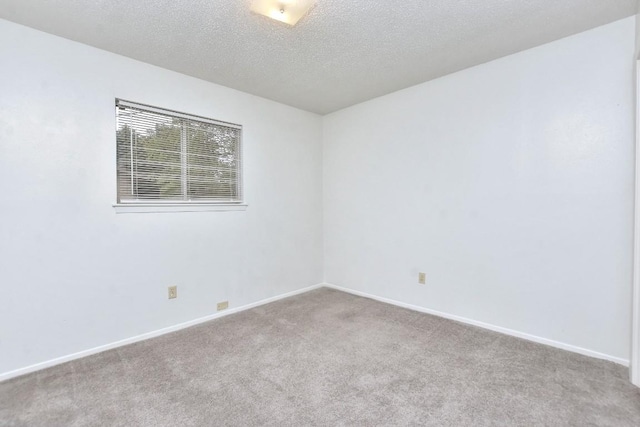 empty room featuring carpet, baseboards, and a textured ceiling