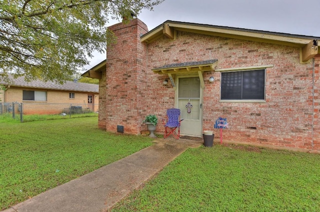 view of front of property with crawl space, brick siding, a front lawn, and fence