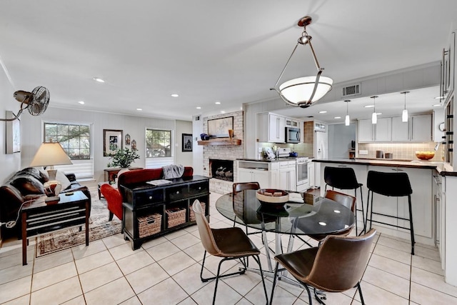 dining room with light tile patterned floors, visible vents, recessed lighting, crown molding, and a brick fireplace