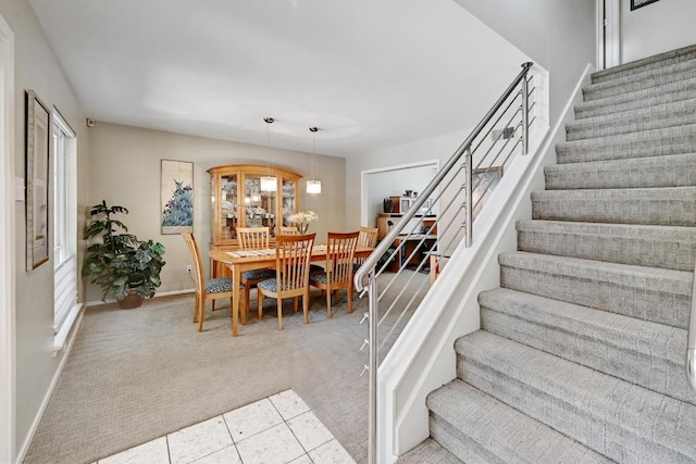 dining room with baseboards, carpet, and stairs