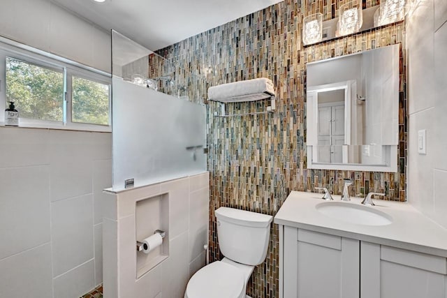 bathroom featuring vanity, tile walls, toilet, and a walk in shower