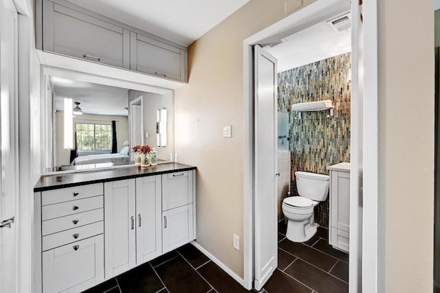 bathroom with tile patterned flooring, visible vents, baseboards, toilet, and vanity