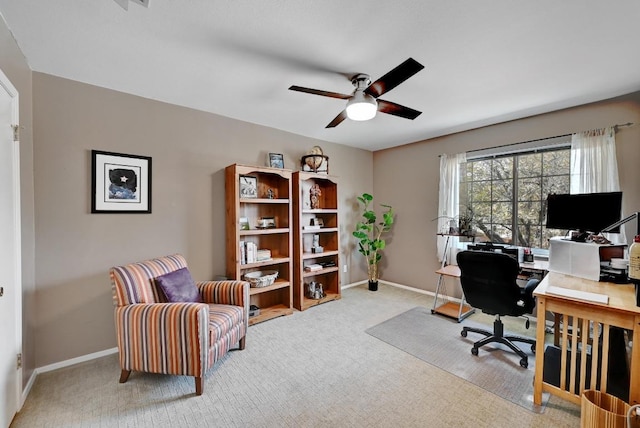 office area featuring baseboards, light carpet, and a ceiling fan