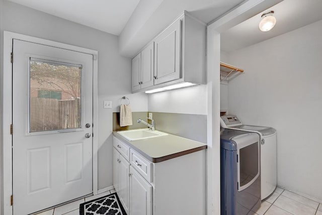 washroom featuring light tile patterned floors, washing machine and dryer, cabinet space, and a sink