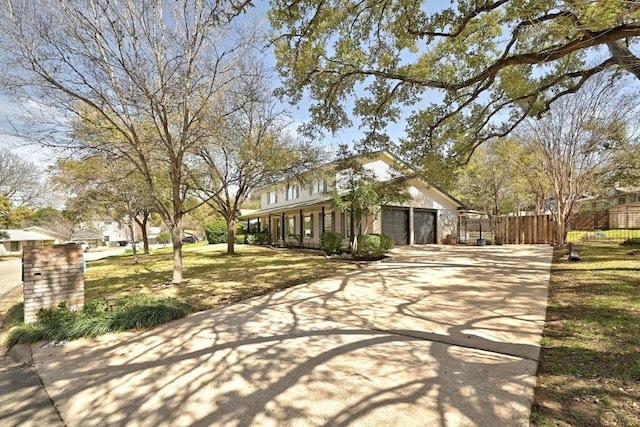 view of front of property with an attached garage, concrete driveway, a front yard, and fence