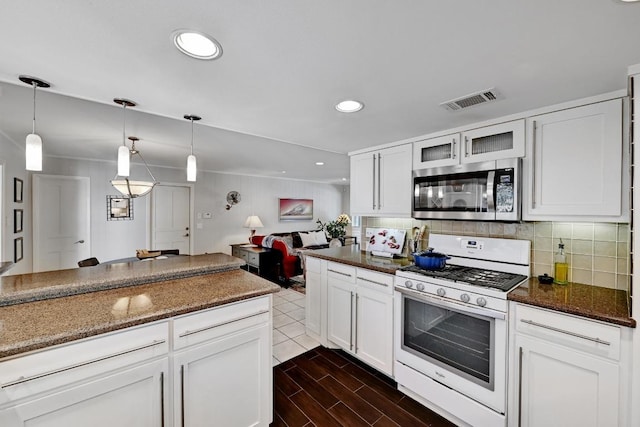 kitchen featuring wood tiled floor, white cabinets, white gas range oven, stainless steel microwave, and tasteful backsplash