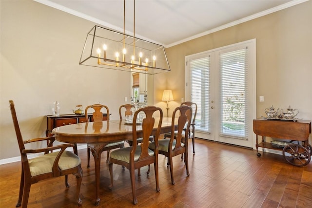 dining area with an inviting chandelier, crown molding, wood finished floors, and baseboards