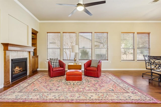 living room featuring hardwood / wood-style floors, crown molding, a fireplace, and baseboards