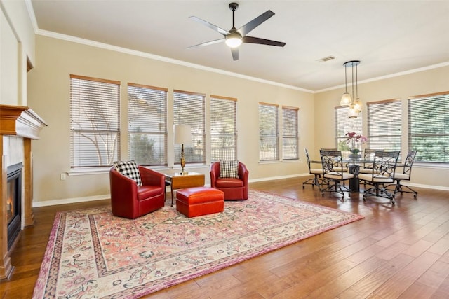 living room featuring visible vents, wood finished floors, crown molding, and a glass covered fireplace