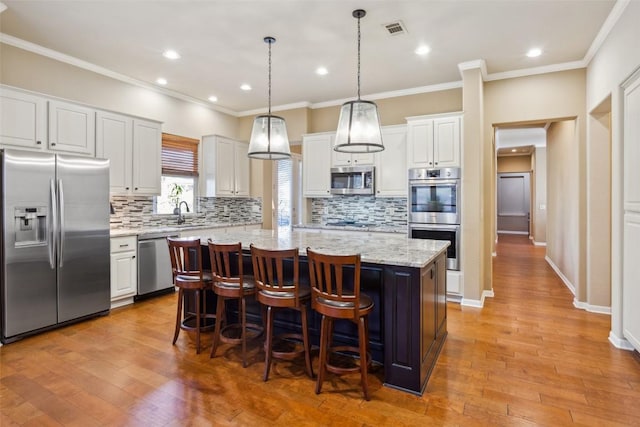 kitchen featuring a center island, visible vents, stainless steel appliances, and light wood-style floors