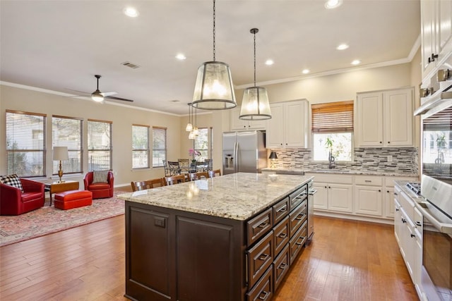 kitchen with dark brown cabinetry, appliances with stainless steel finishes, white cabinetry, and hardwood / wood-style flooring