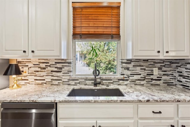 kitchen featuring dishwasher, tasteful backsplash, white cabinetry, and a sink