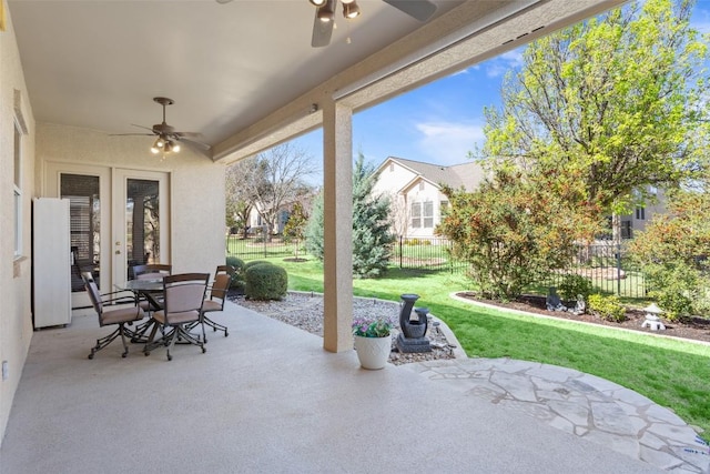 view of patio with outdoor dining area, a ceiling fan, fence, and french doors