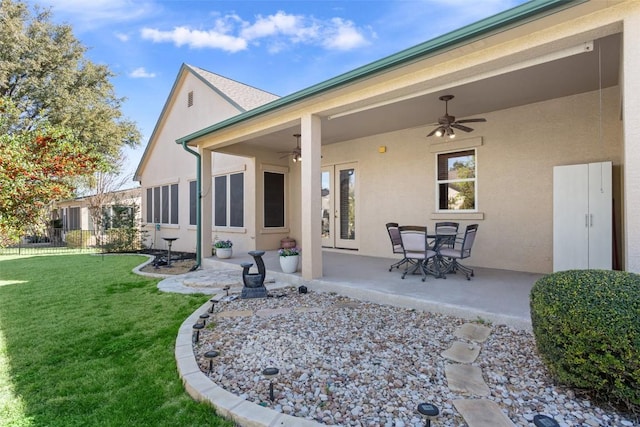 back of house with stucco siding, fence, a yard, ceiling fan, and a patio area