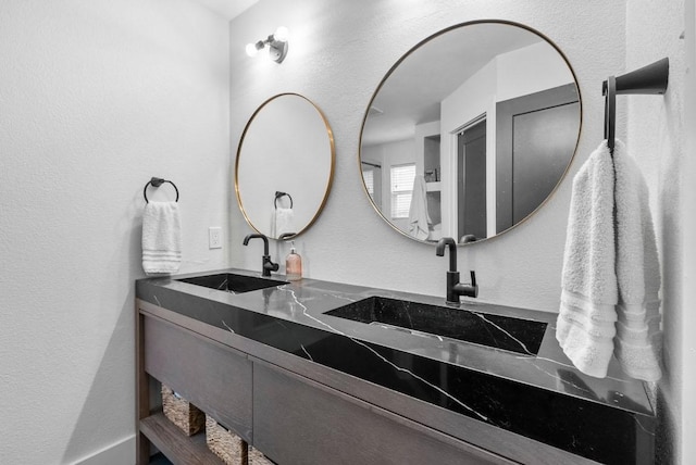 bathroom with a sink, double vanity, and a textured wall