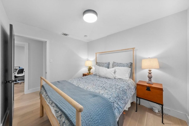 bedroom featuring visible vents, baseboards, and wood finished floors