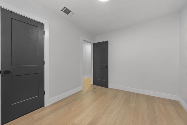 empty room featuring baseboards, visible vents, and light wood finished floors