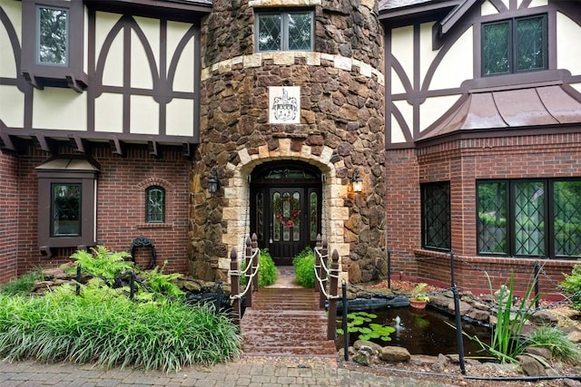 entrance to property featuring a standing seam roof, brick siding, stone siding, and metal roof