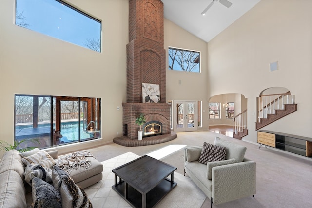 carpeted living room with baseboards, a fireplace, arched walkways, stairs, and french doors