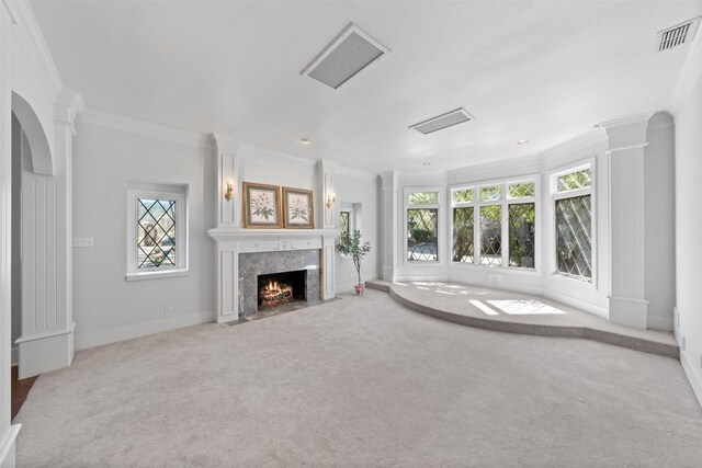 unfurnished living room with visible vents, ornate columns, carpet floors, a high end fireplace, and crown molding