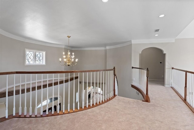 hallway featuring visible vents, ornamental molding, arched walkways, an inviting chandelier, and carpet flooring