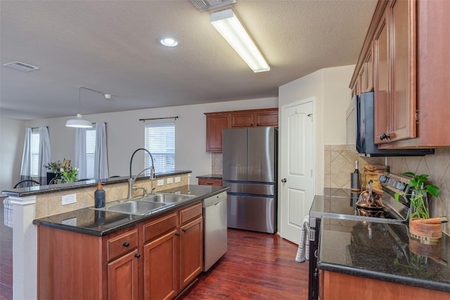 714 Alamo Plaza Dr, Cedar Park, TX 78613 - kitchen with stainless steel appliances, a textured ceiling, decorative backsplash, dark wood finished floors, and an island with sink