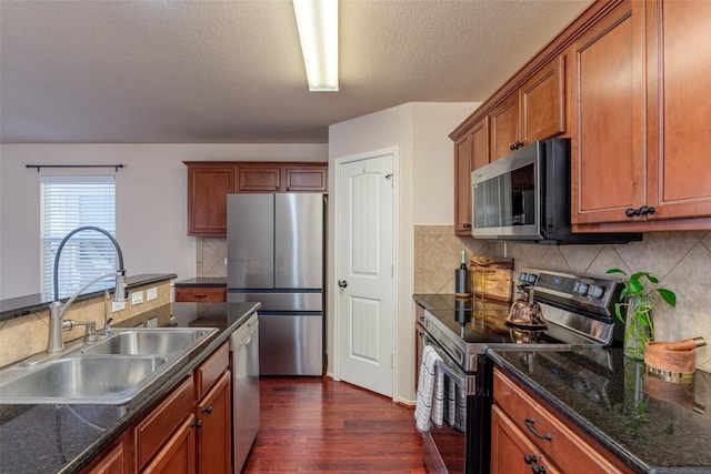 kitchen with a sink, backsplash, brown cabinetry, stainless steel appliances, and dark wood-style flooring