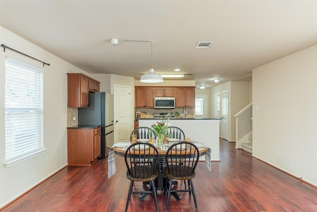 dining space featuring dark wood-type flooring, stairway, baseboards, and visible vents