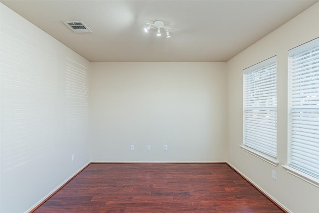 empty room with visible vents, baseboards, and wood finished floors