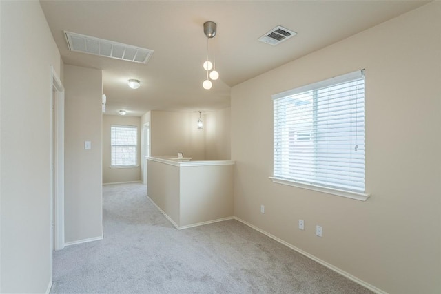 carpeted spare room featuring baseboards and visible vents